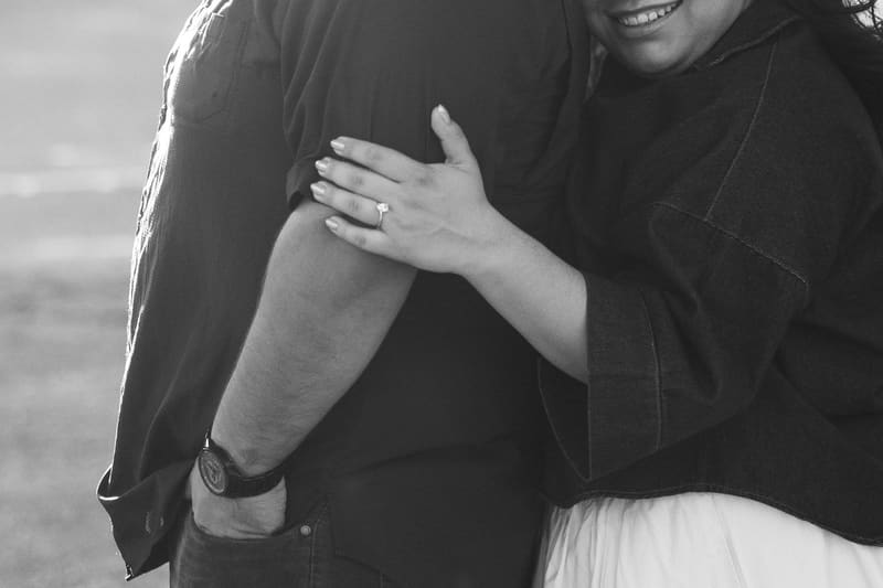 La mano de Karla con su anillo de compromiso sobre el brazo de Christian, en blanco y negro